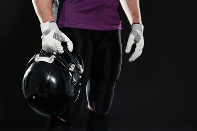 American football player with helmet wearing uniform on dark background, closeup