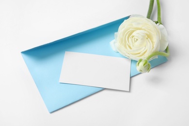 Photo of Envelope with card and beautiful ranunculus flower on white background. Space for text