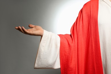 Photo of Jesus Christ reaching out his hand on grey background, closeup view