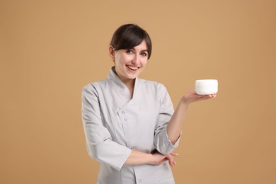 Cosmetologist with cosmetic product on beige background