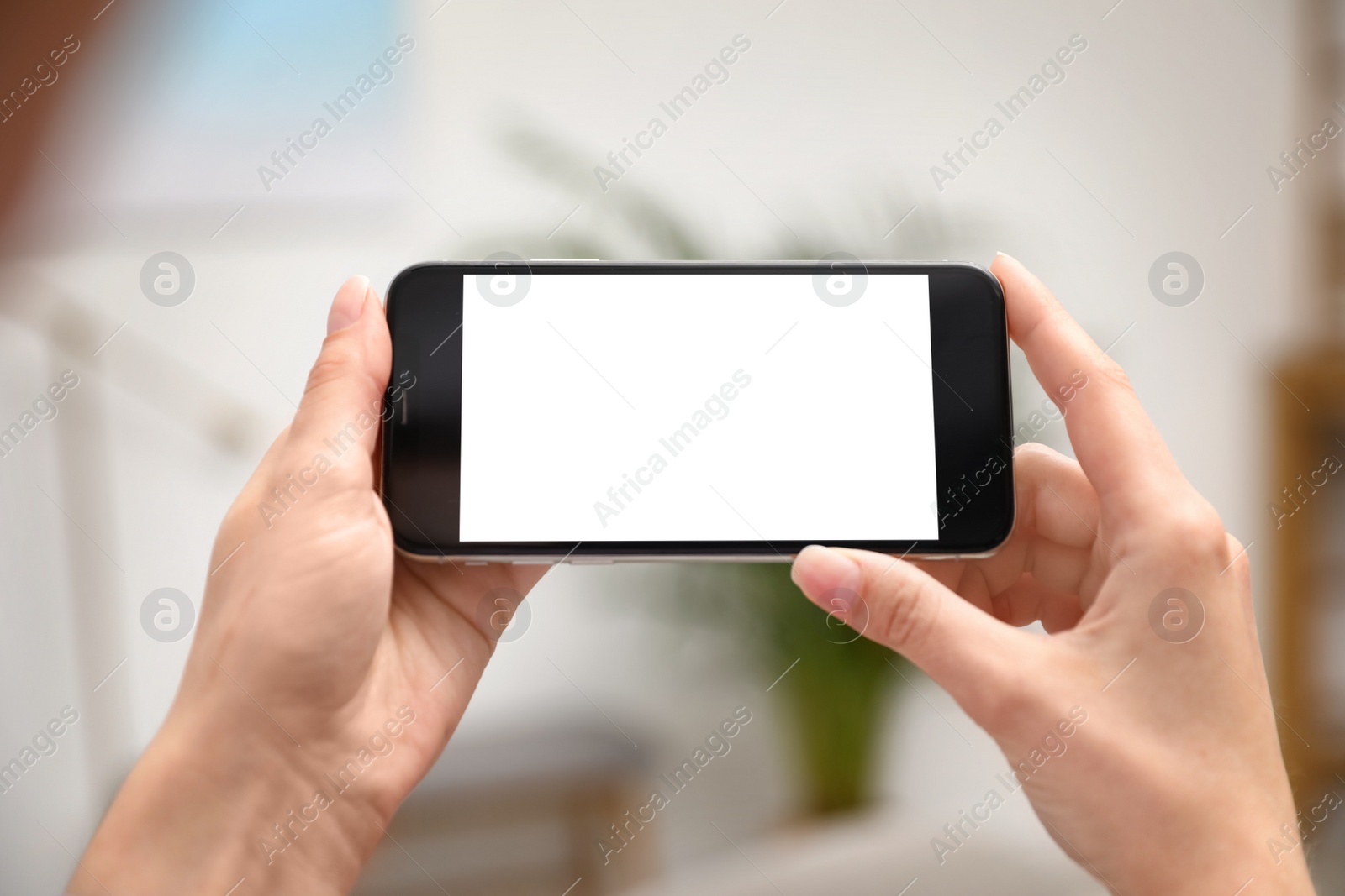 Photo of Woman holding smartphone with blank screen indoors, closeup of hands. Space for text