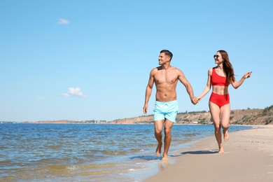 Photo of Woman in bikini and her boyfriend on beach, space for text. Happy couple