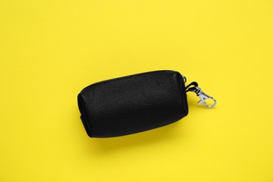 Photo of Stylish leather keys holder on yellow background, top view