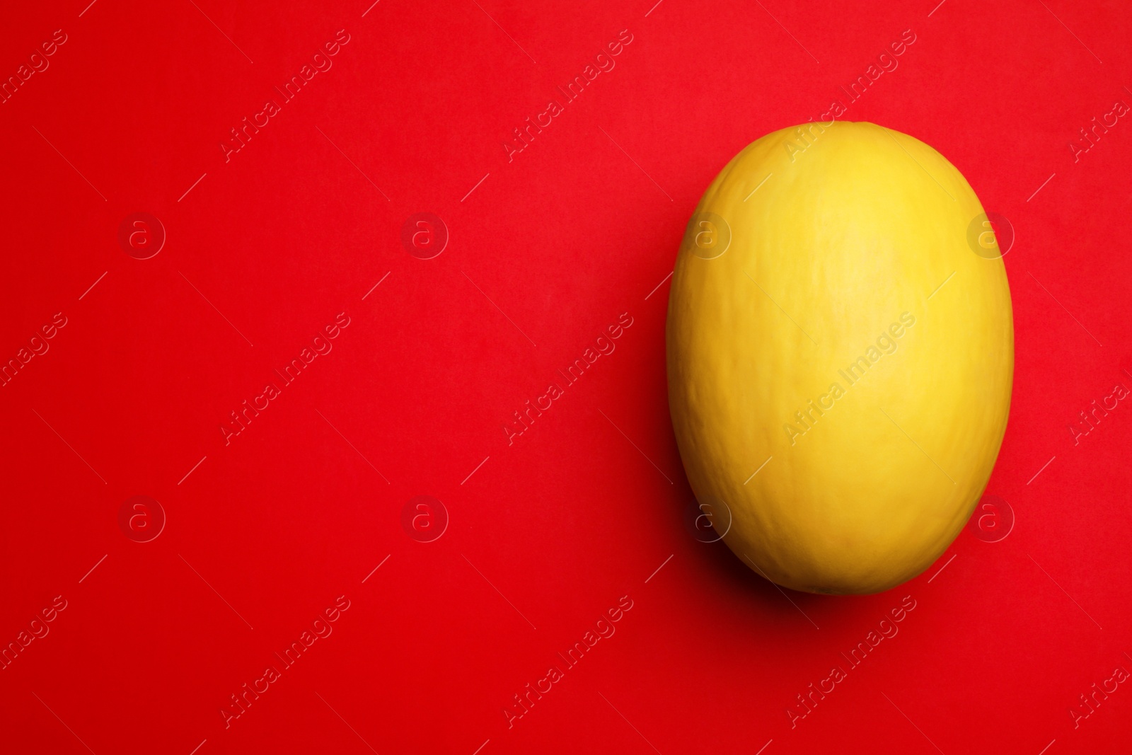 Photo of Whole ripe tasty melon on red background, top view. Space for text