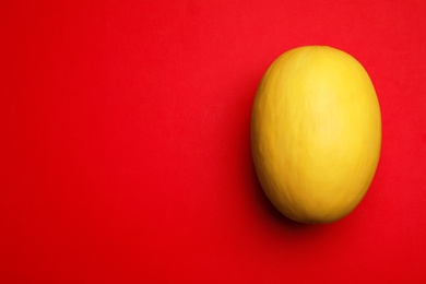 Whole ripe tasty melon on red background, top view. Space for text