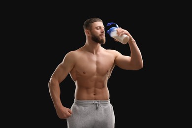 Photo of Young man with muscular body drinking protein shake on black background