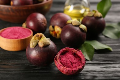 Purple mangosteen powder and fruits on black wooden table