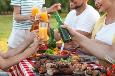 Happy friends with drinks and food at barbecue party in park, closeup