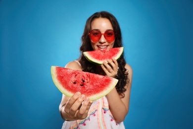 Beautiful young woman against blue background, focus on hand with watermelon