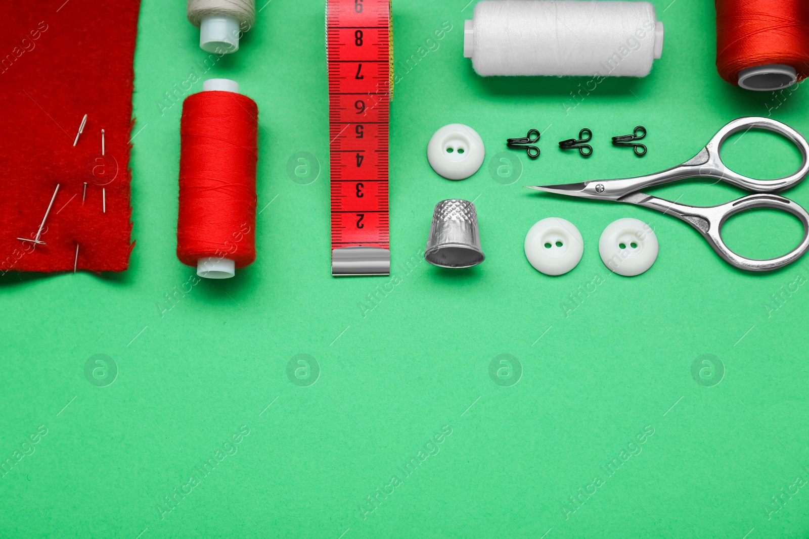 Photo of Flat lay composition with thimble and different sewing tools on green background. Space for text
