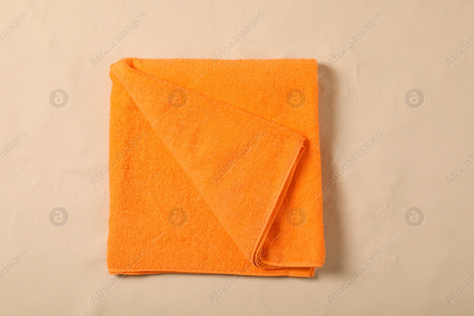 Photo of Orange beach towel on sand, top view