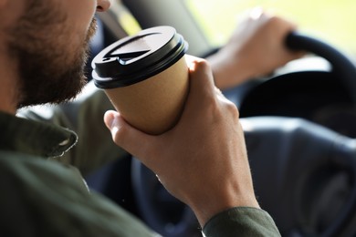 Photo of To-go drink. Man drinking coffee while driving his car, closeup