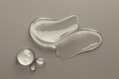 Sample of clear cosmetic gel on grey background, top view