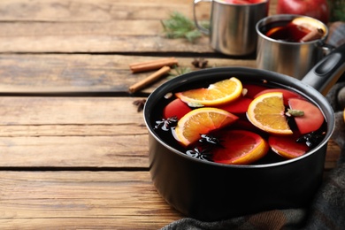 Photo of Delicious mulled wine and ingredients on wooden table. Space for text