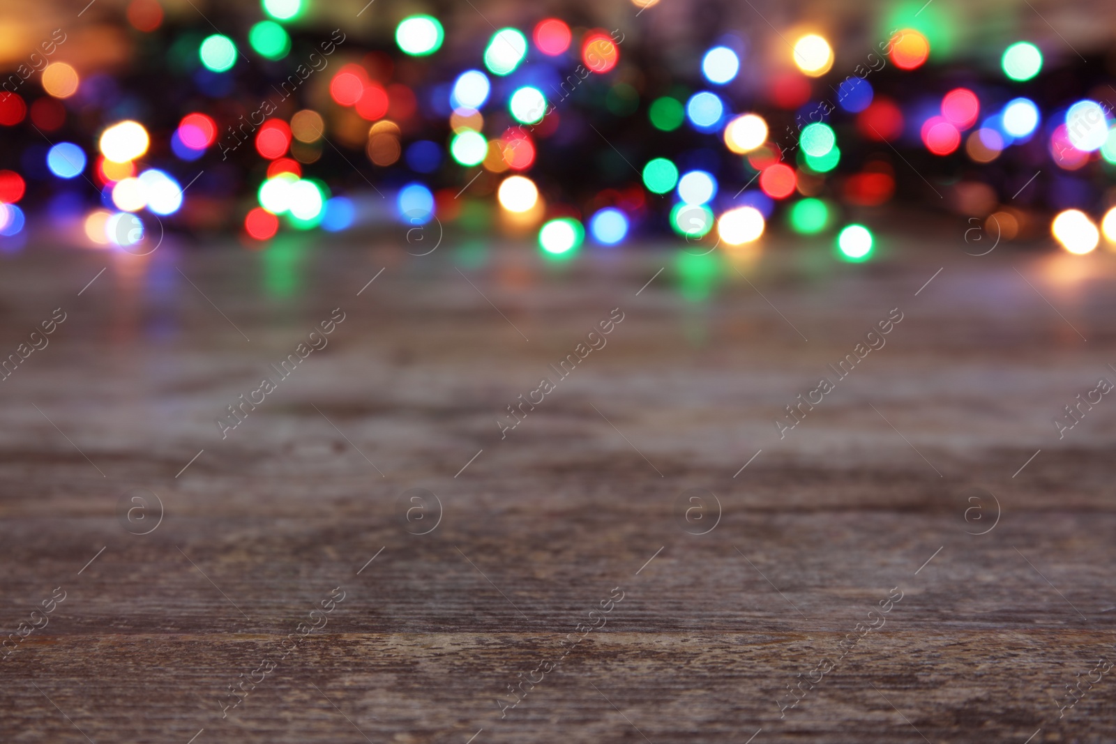 Photo of Wooden table and blurred Christmas lights on background