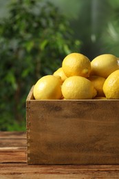 Photo of Fresh lemons in crate on wooden table