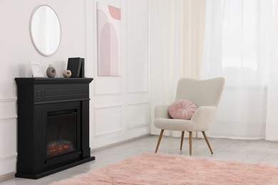 Photo of Black stylish fireplace near soft armchair in cosy living room