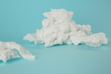 Photo of Used paper tissues on light blue background, closeup