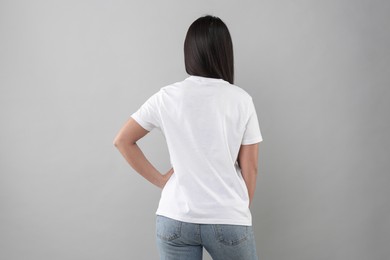 Photo of Woman wearing white t-shirt on light grey background, back view