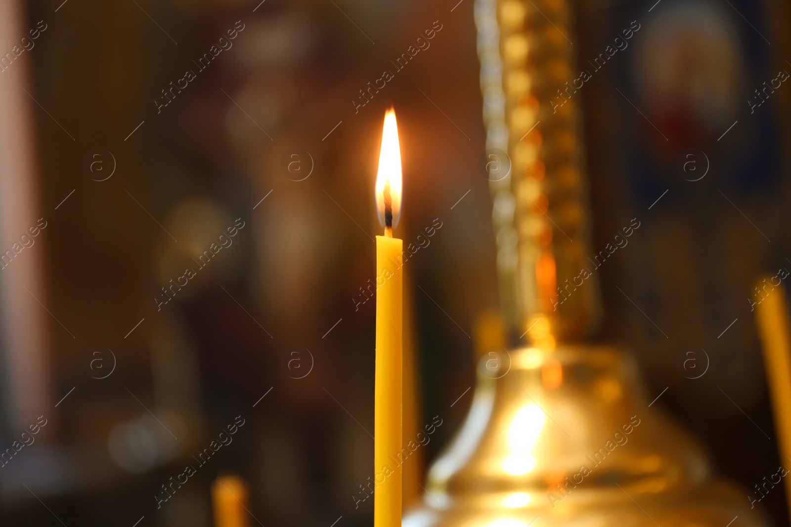 Photo of One burning candle in church, closeup view