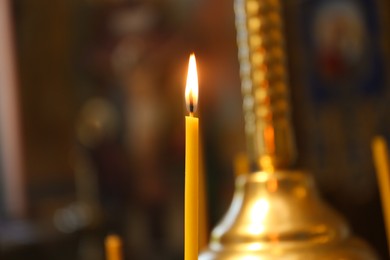 Photo of One burning candle in church, closeup view