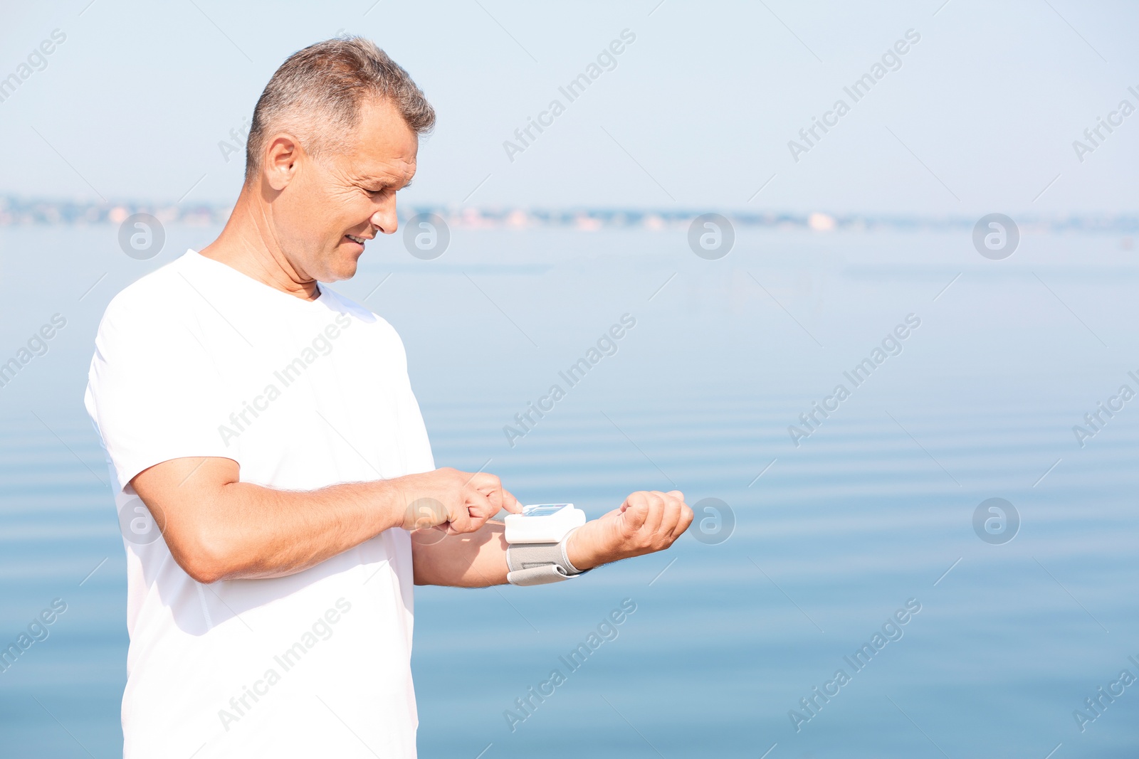 Photo of Man checking pulse outdoors on sunny day