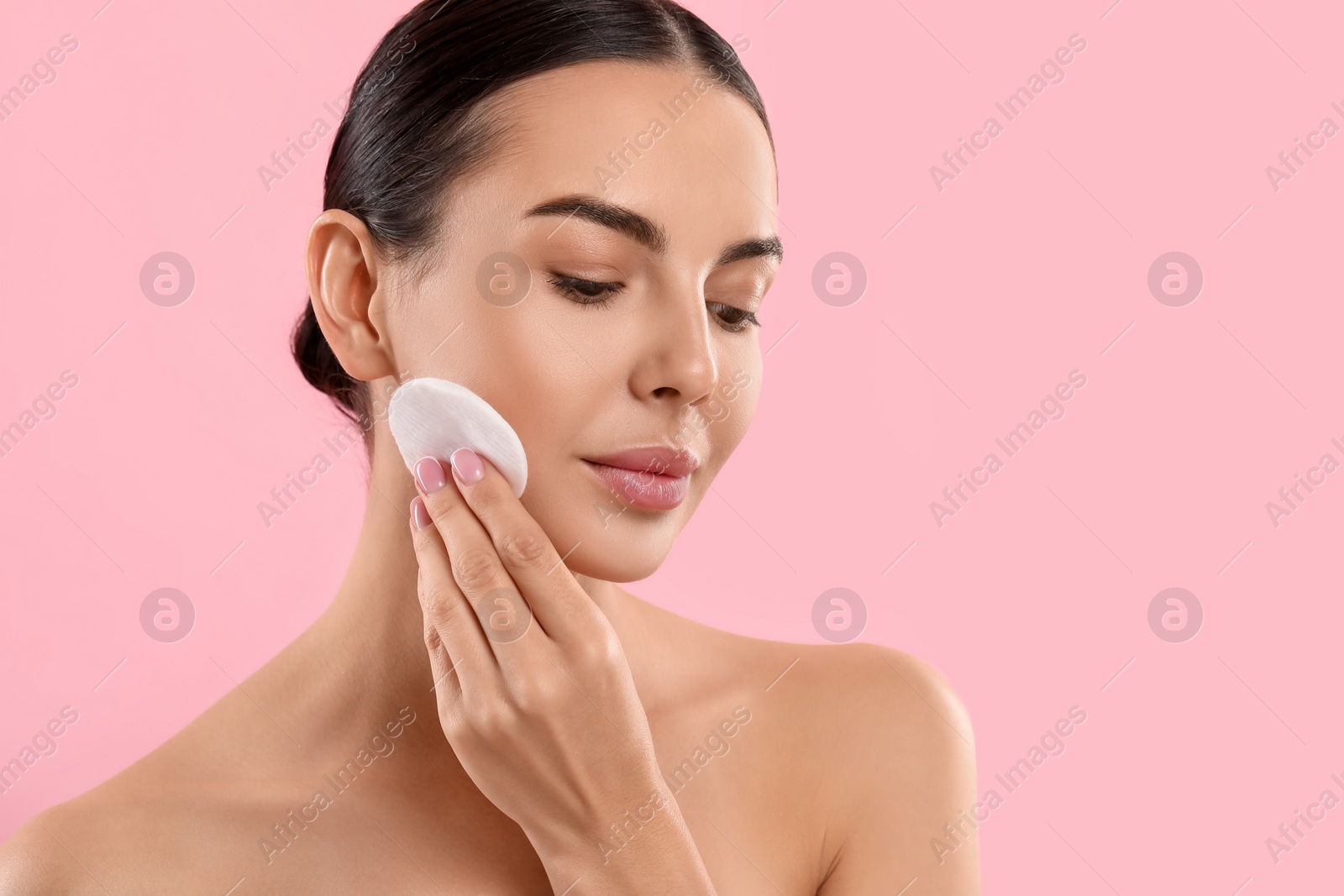 Photo of Beautiful woman removing makeup with cotton pad on pink background. Space for text