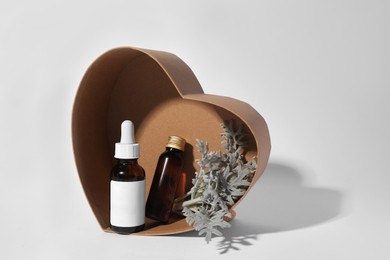 Photo of Heart shaped box with cosmetic products and silver leaves on white background