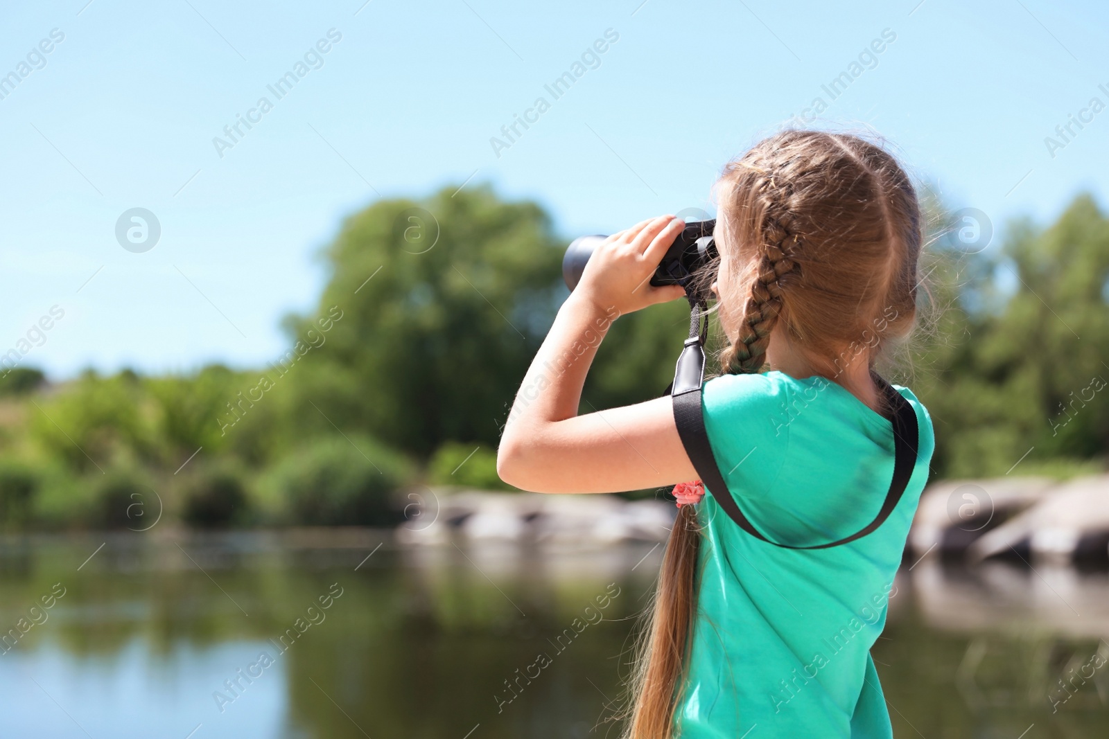 Photo of Little girl with binoculars outdoors. Summer camp