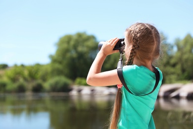 Little girl with binoculars outdoors. Summer camp