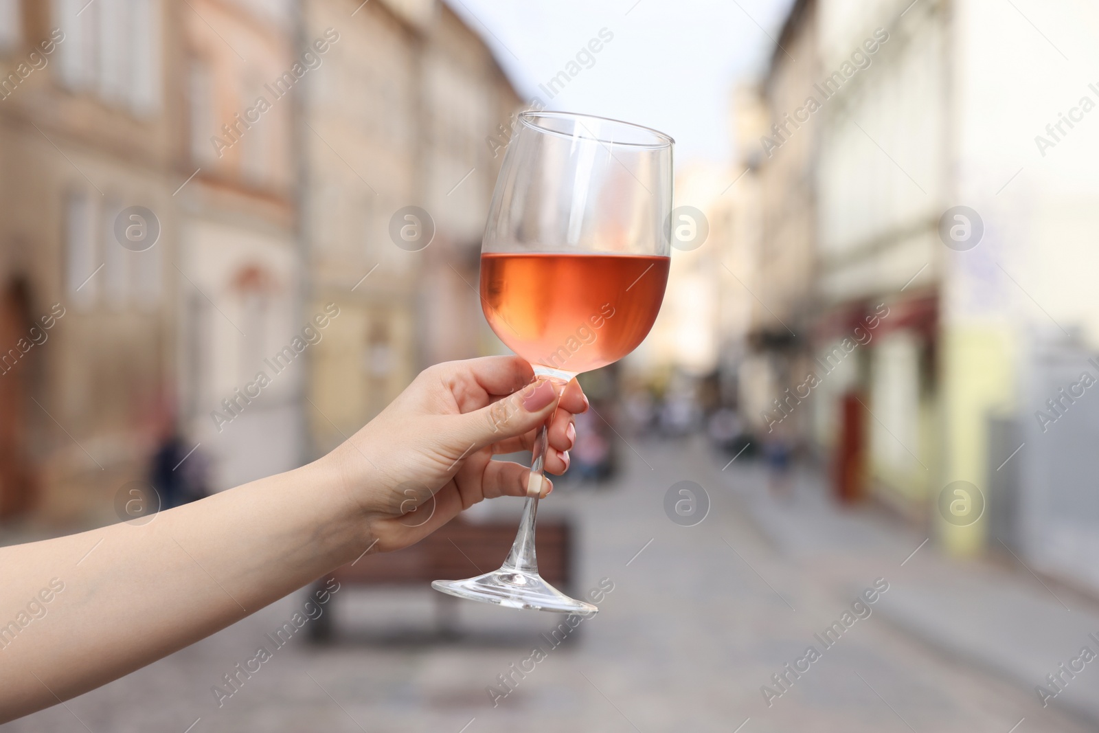 Photo of Woman holding glass of rose wine outdoors, closeup