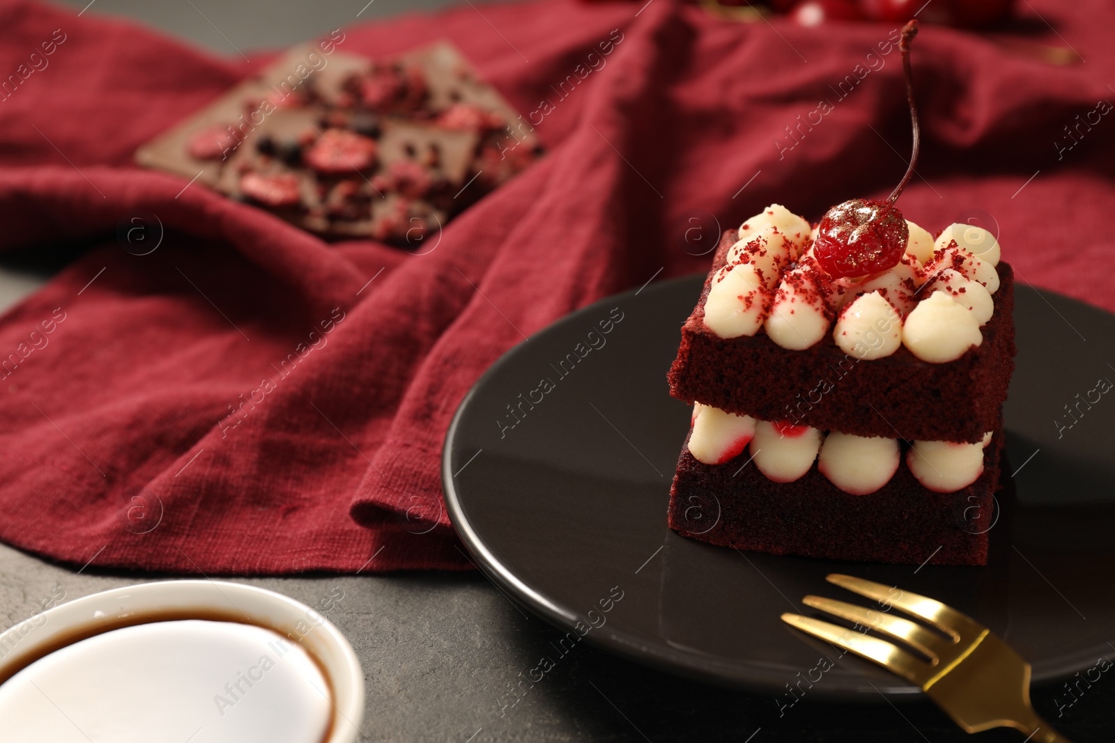 Photo of Piece of red velvet cake and fork on table, closeup with space for text