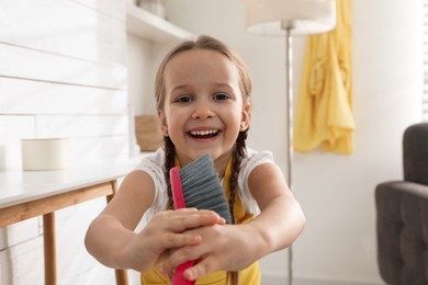 Photo of Cute little girl with brush singing at home