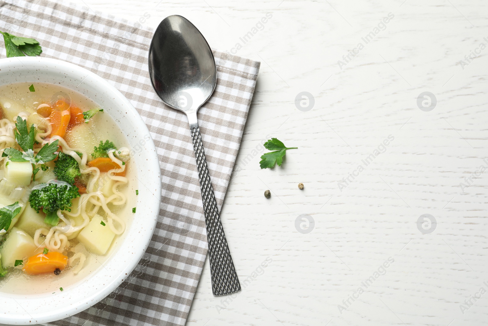 Photo of Bowl of fresh homemade vegetable soup served on white wooden table, flat lay. Space for text