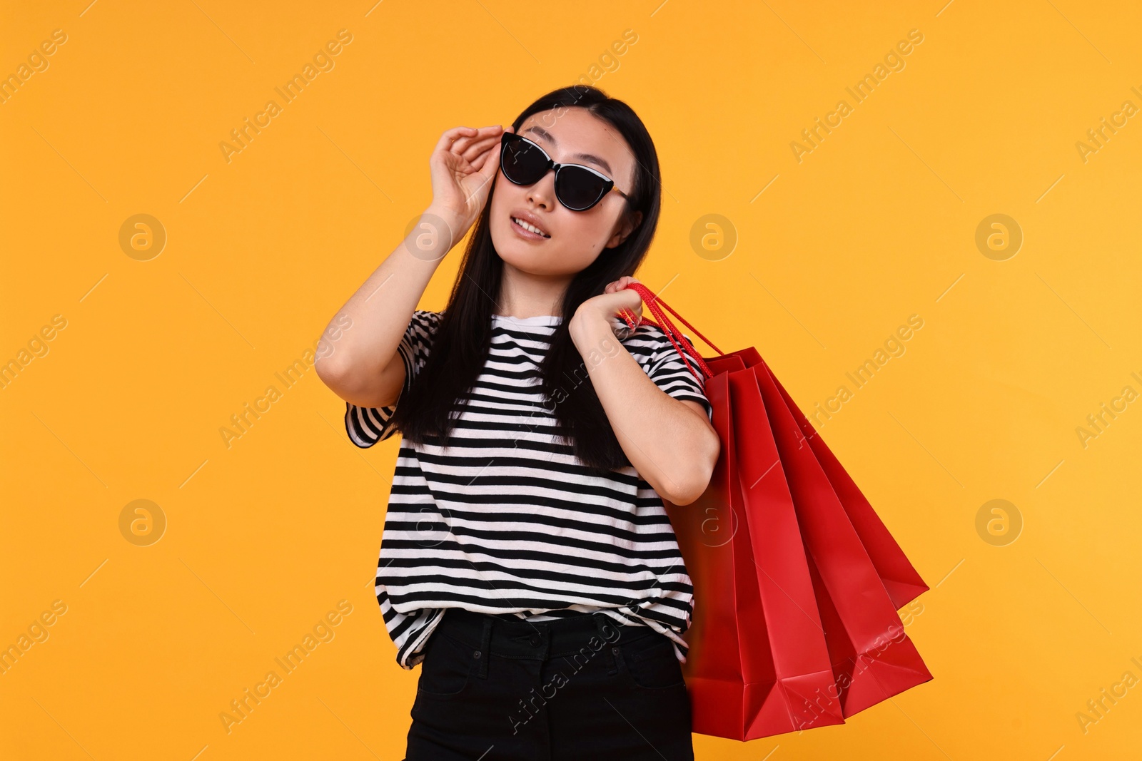 Photo of Beautiful woman with shopping bags on yellow background