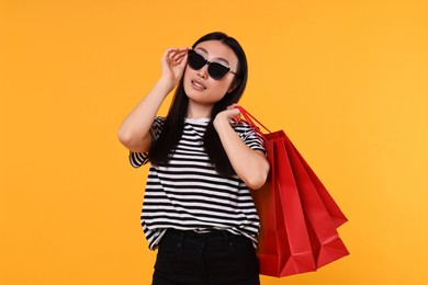 Beautiful woman with shopping bags on yellow background