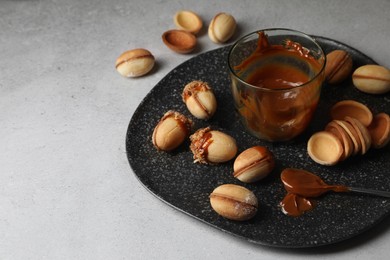 Photo of Delicious walnut shaped cookies with condensed milk on grey table. Space for text