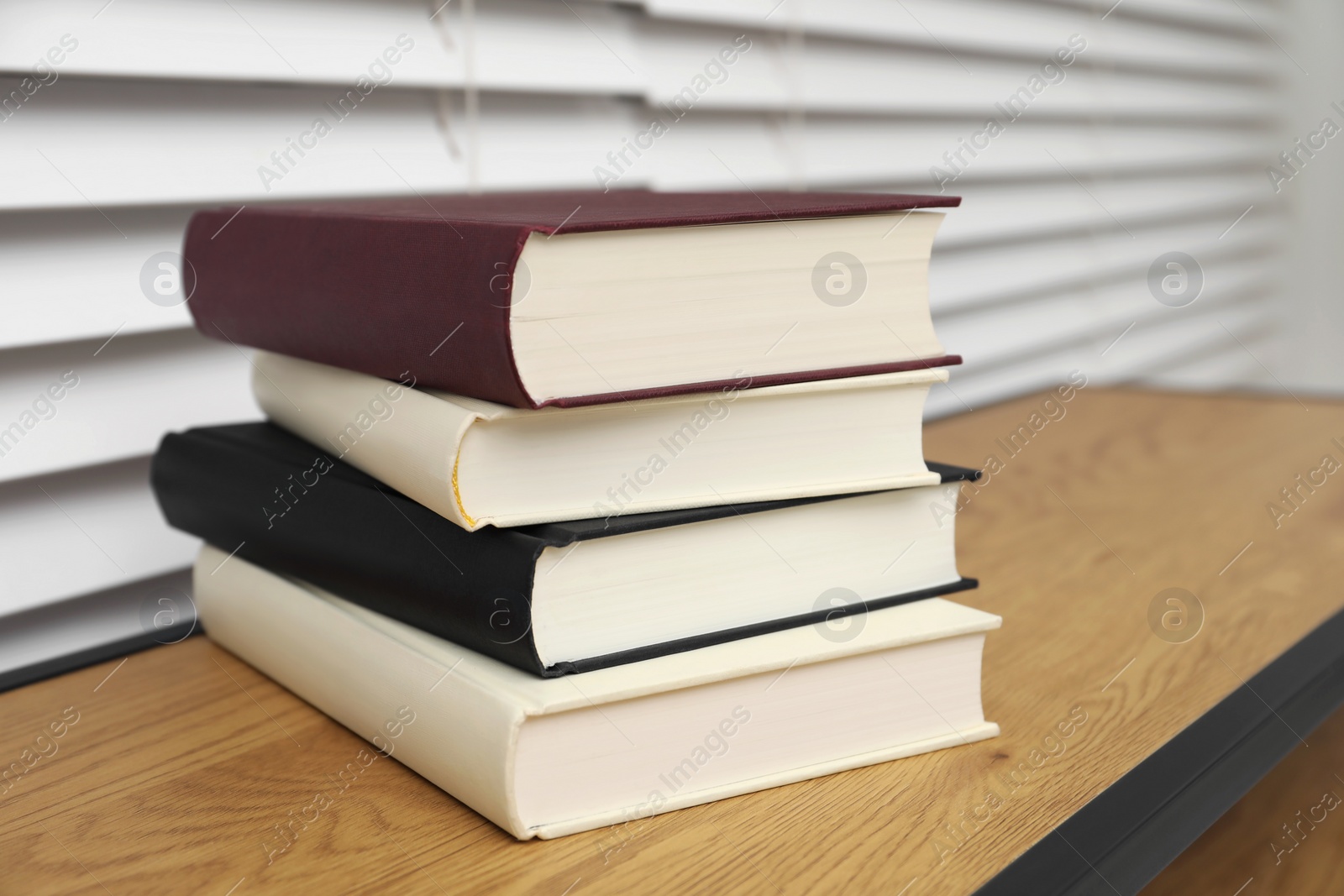 Photo of Stack of hardcover books on wooden table indoors, closeup