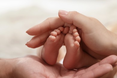 Mother and father holding their newborn baby, closeup view on feet. Lovely family