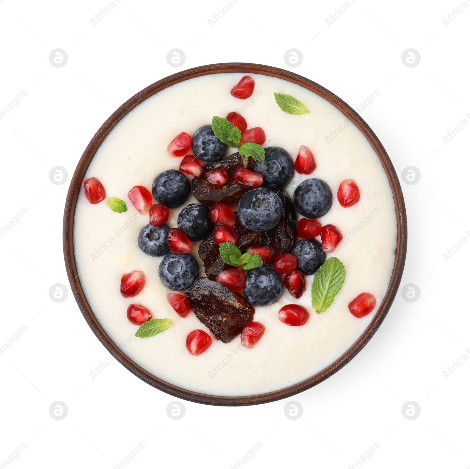 Photo of Delicious semolina pudding with blueberries, pomegranate, dates and mint in bowl isolated on white, top view