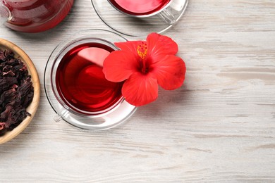 Photo of Delicious hibiscus tea and beautiful flower on light wooden table, flat lay. Space for text