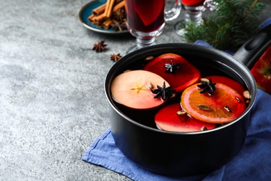 Delicious mulled wine and ingredients on grey table. Space for text