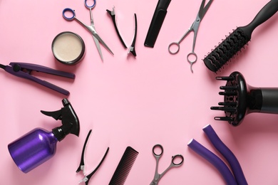 Photo of Frame made of scissors and other hairdresser's accessories on pink background, flat lay. Space for text