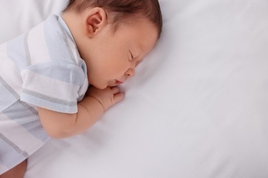 Photo of Cute newborn baby sleeping on white bed, top view. Space for text