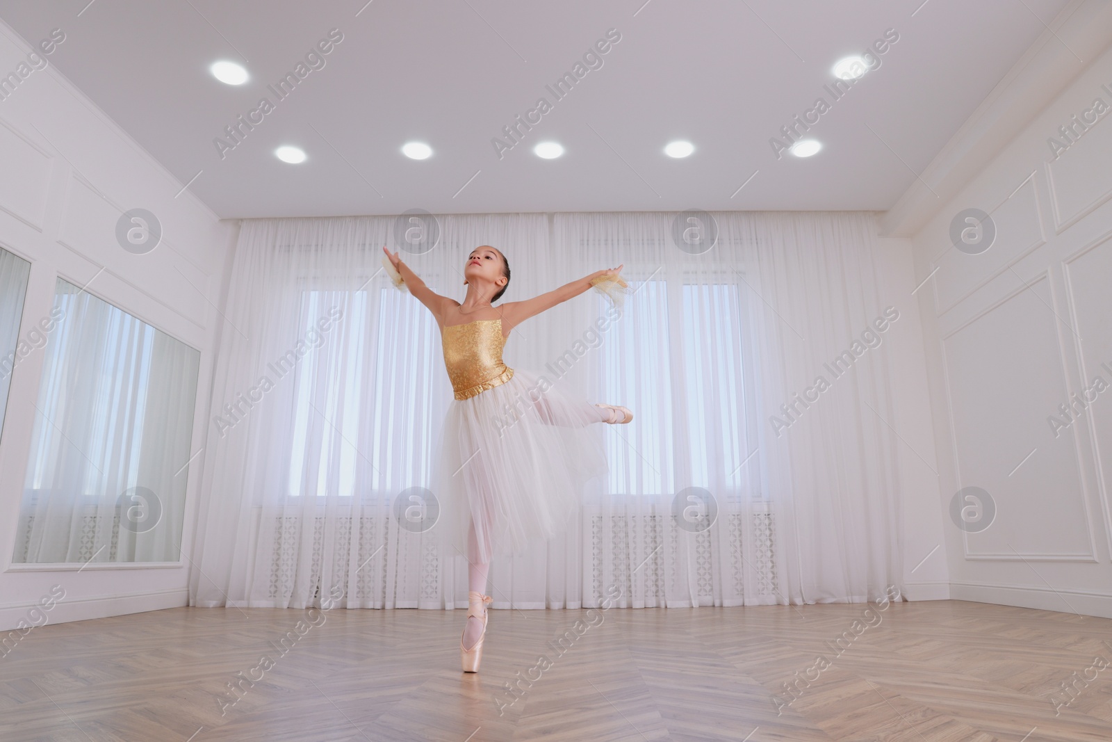 Photo of Beautifully dressed little ballerina dancing in studio