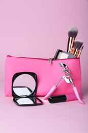 Photo of Stylish pocket mirror and cosmetic bag with makeup products on violet background