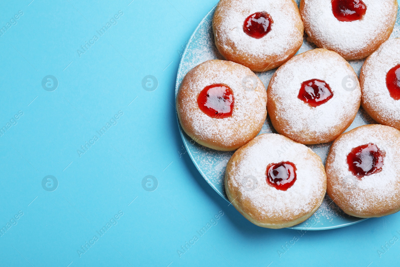 Photo of Hanukkah doughnuts with jelly and sugar powder served on blue background, top view. Space for text