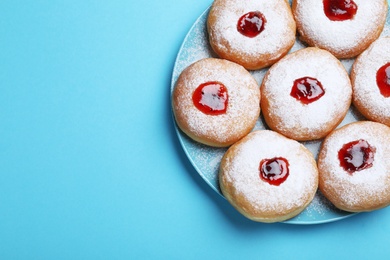 Photo of Hanukkah doughnuts with jelly and sugar powder served on blue background, top view. Space for text