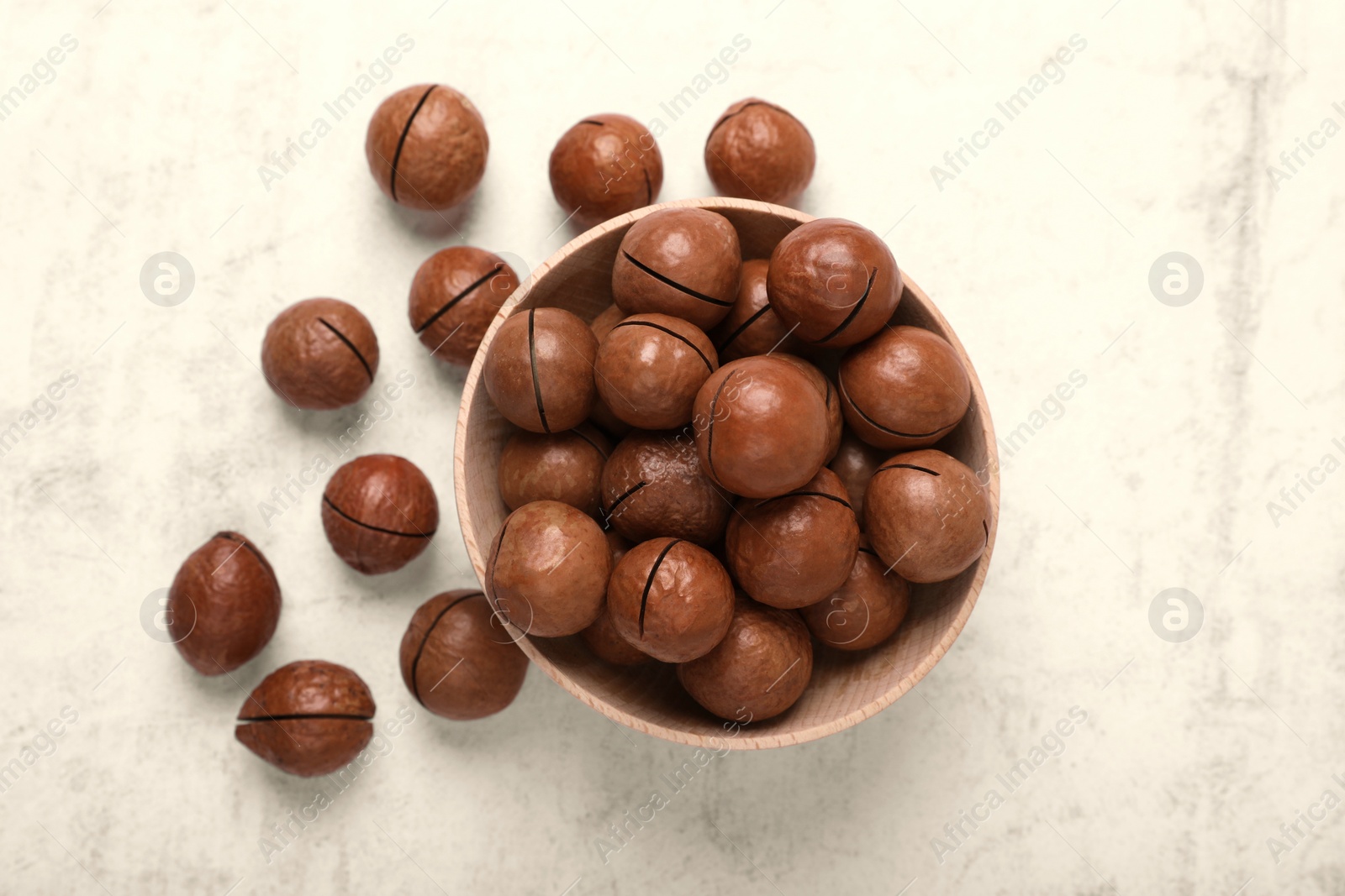 Photo of Delicious organic Macadamia nuts on light gray table, flat lay