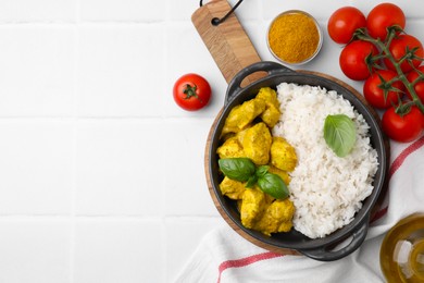 Photo of Delicious rice, chicken with curry sauce and products on white tiled table, flat lay. Space for text